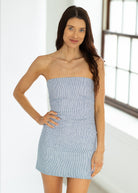 Woman wearing a strapless blue dress indoors with a neutral background