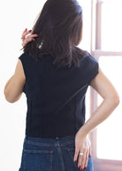 Person wearing a black sleeveless top and blue jeans with a blurred background