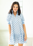 Woman wearing a light blue dress with dark polka dots on a white background