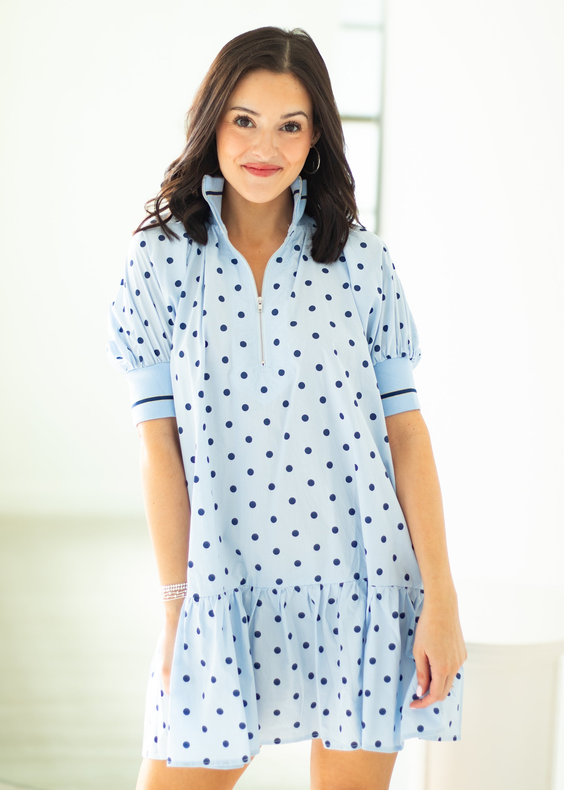 Woman wearing a light blue dress with dark polka dots on a white background