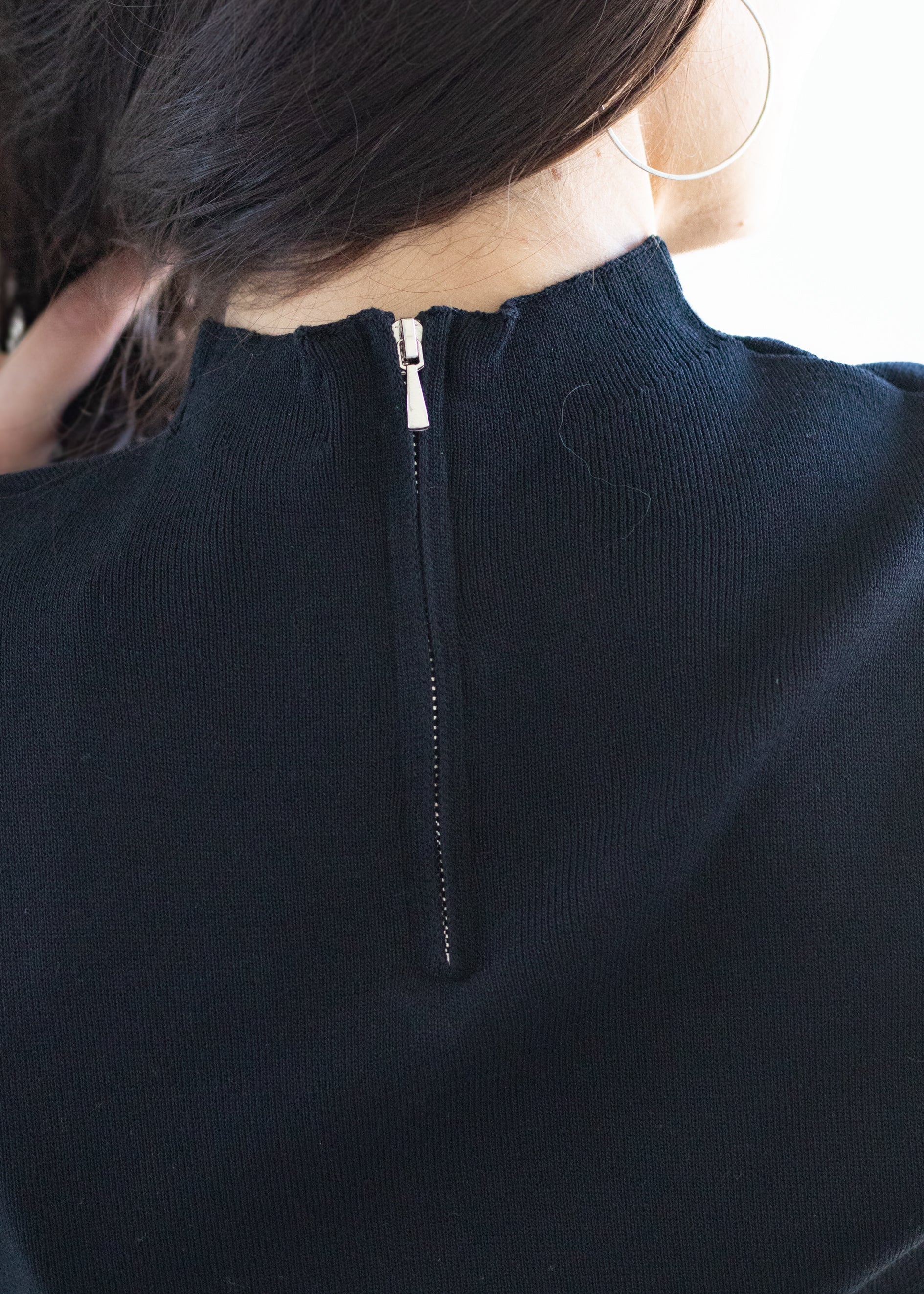 Close-up of a person wearing a black shirt with silver zipper detail.