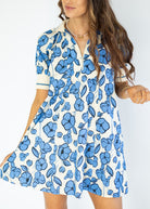 Woman wearing a white dress with blue floral pattern on a plain background
