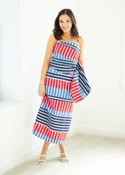 Woman wearing a red, white, and blue striped dress holding a matching bag on a white background