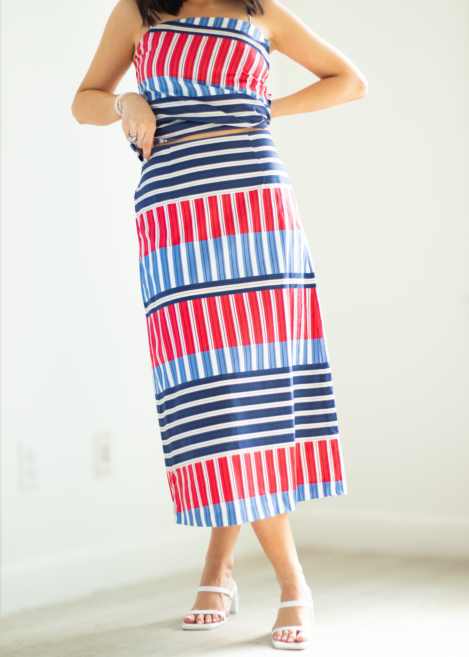 Woman wearing a red, white, and blue striped dress on a plain background