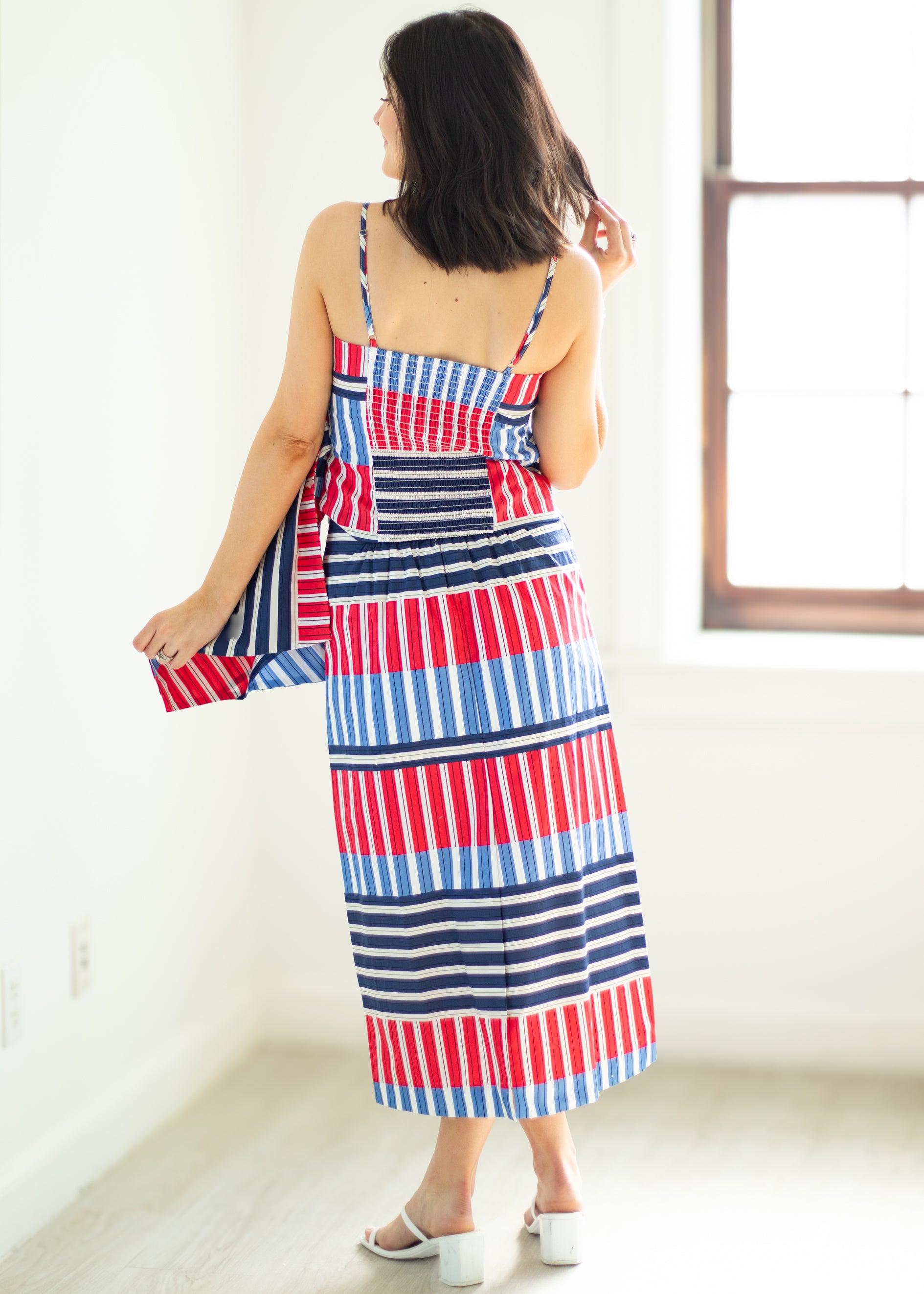 Woman wearing a red, white, and blue striped dress in a bright room.