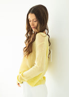 Woman wearing a yellow sweater against a white wall