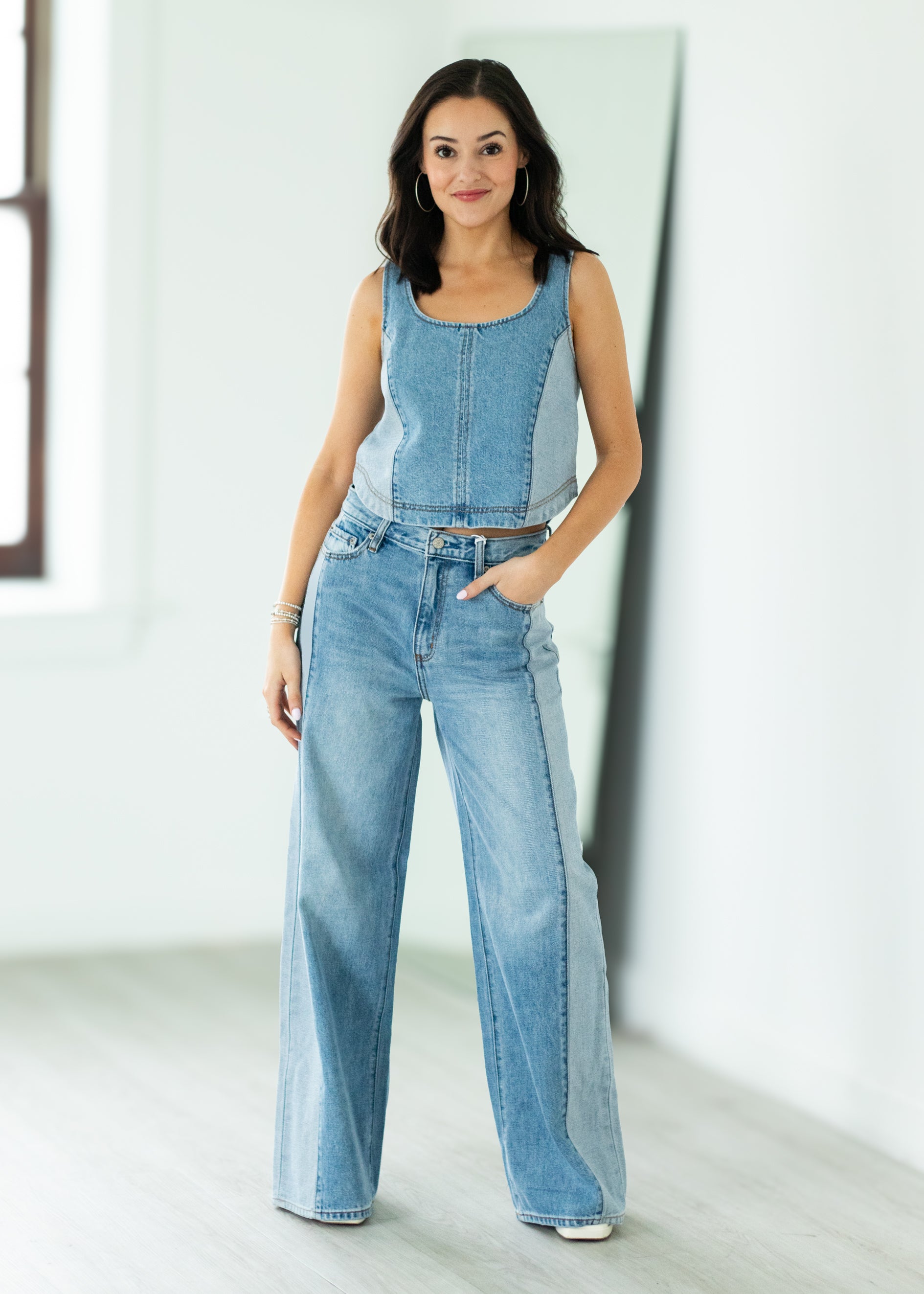 Woman wearing a denim set standing in a bright room.