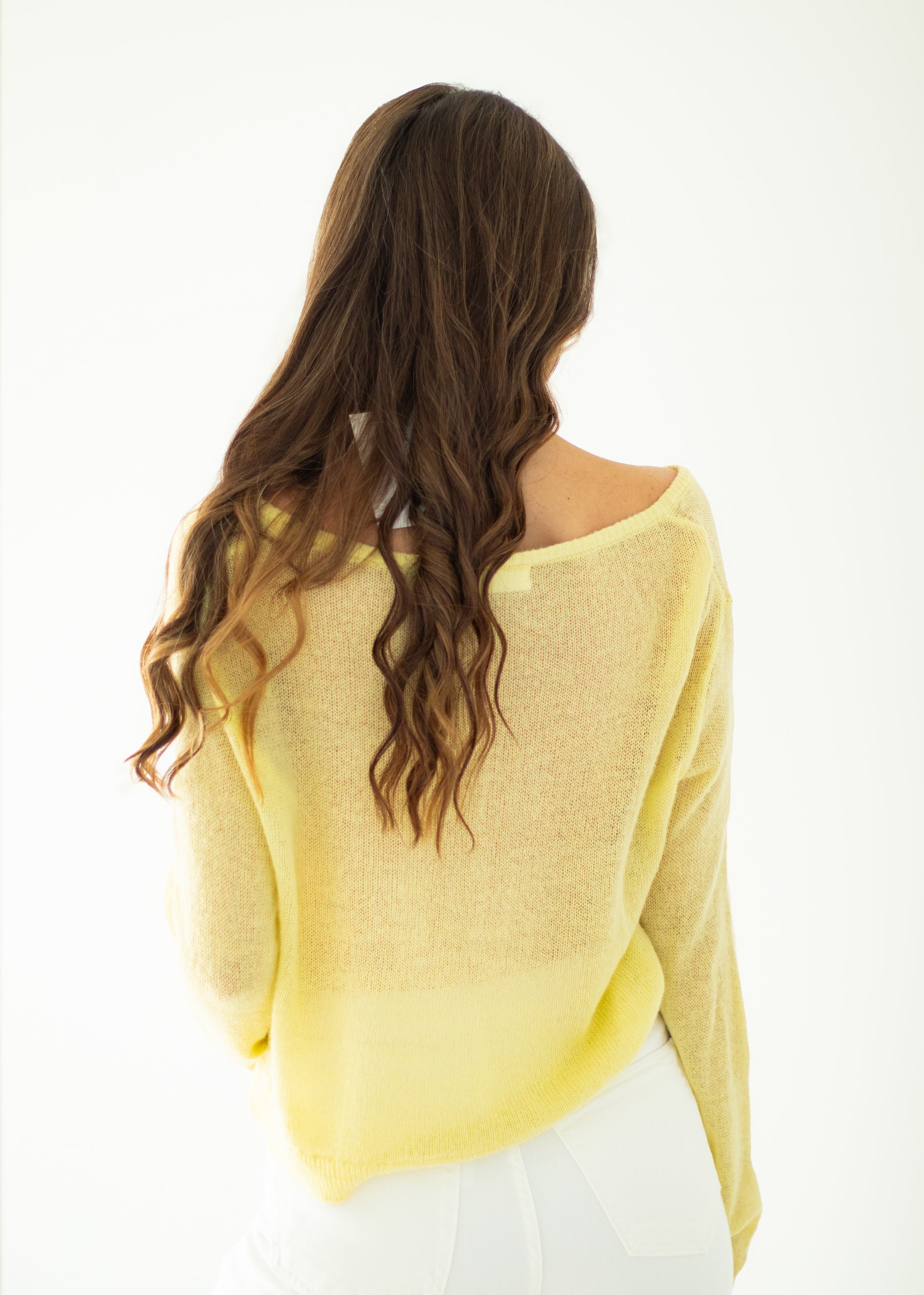 Woman wearing a yellow sweater with a plain background