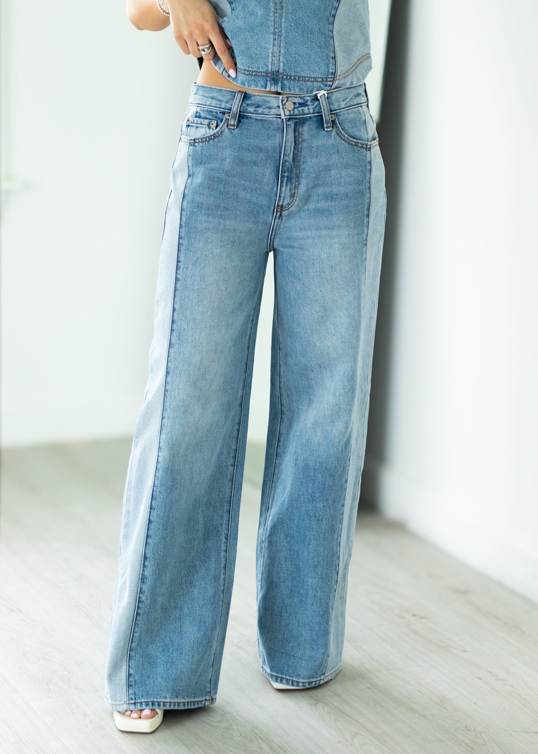 Woman wearing a denim set standing in a bright room.