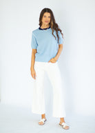Woman wearing a light blue sweater and white pants on a white background