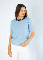 Woman wearing a light blue sweater with a white background