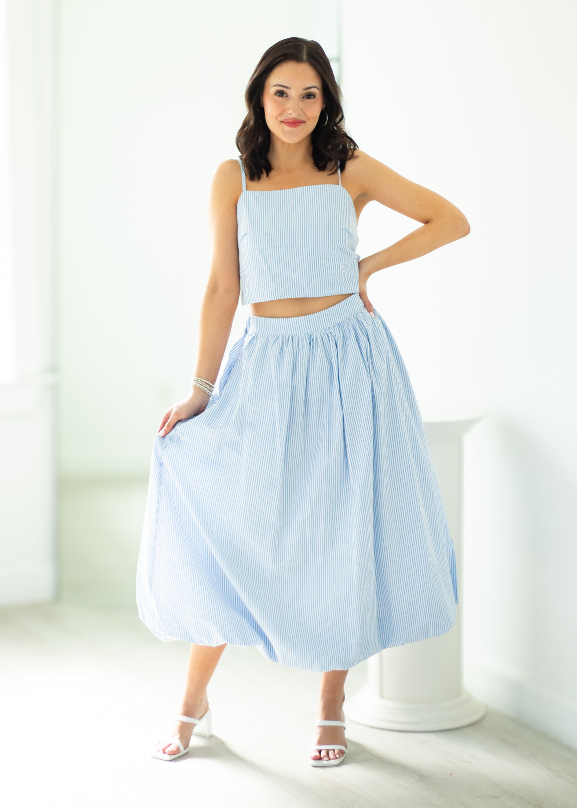 Woman wearing a light blue outfit with a top and skirt on a white background
