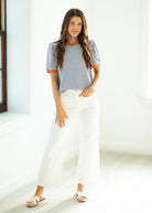 Woman wearing a striped shirt and white pants in a bright room