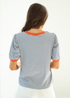 Woman wearing a striped shirt with orange trim on a white background