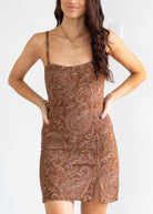 Woman wearing a brown patterned dress against a white background