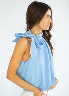 Woman wearing a light blue top with a bow detail on a white background