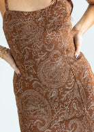 Brown patterned dress worn by a person on a white background