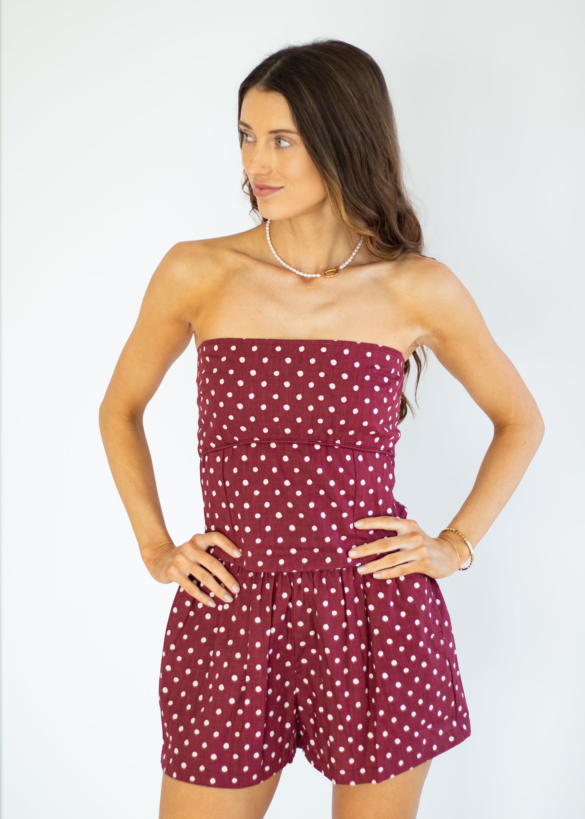 Woman wearing a strapless polka dot romper against a white background