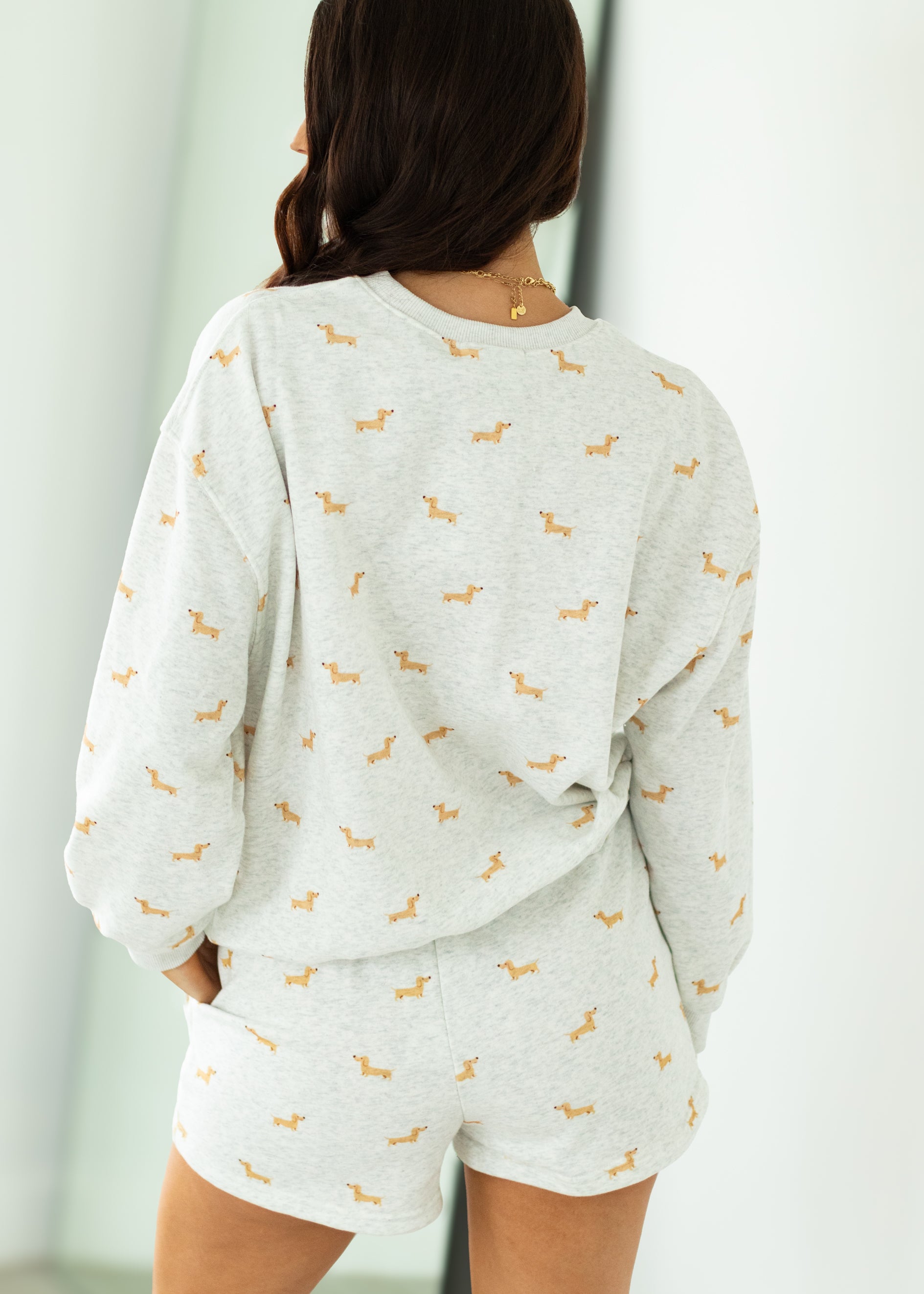 Person wearing a light gray pajama set with small patterns, standing against a neutral background.