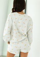 Person wearing a light gray pajama set with small patterns, standing against a neutral background.
