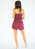 Woman wearing a red polka dot romper on a white background