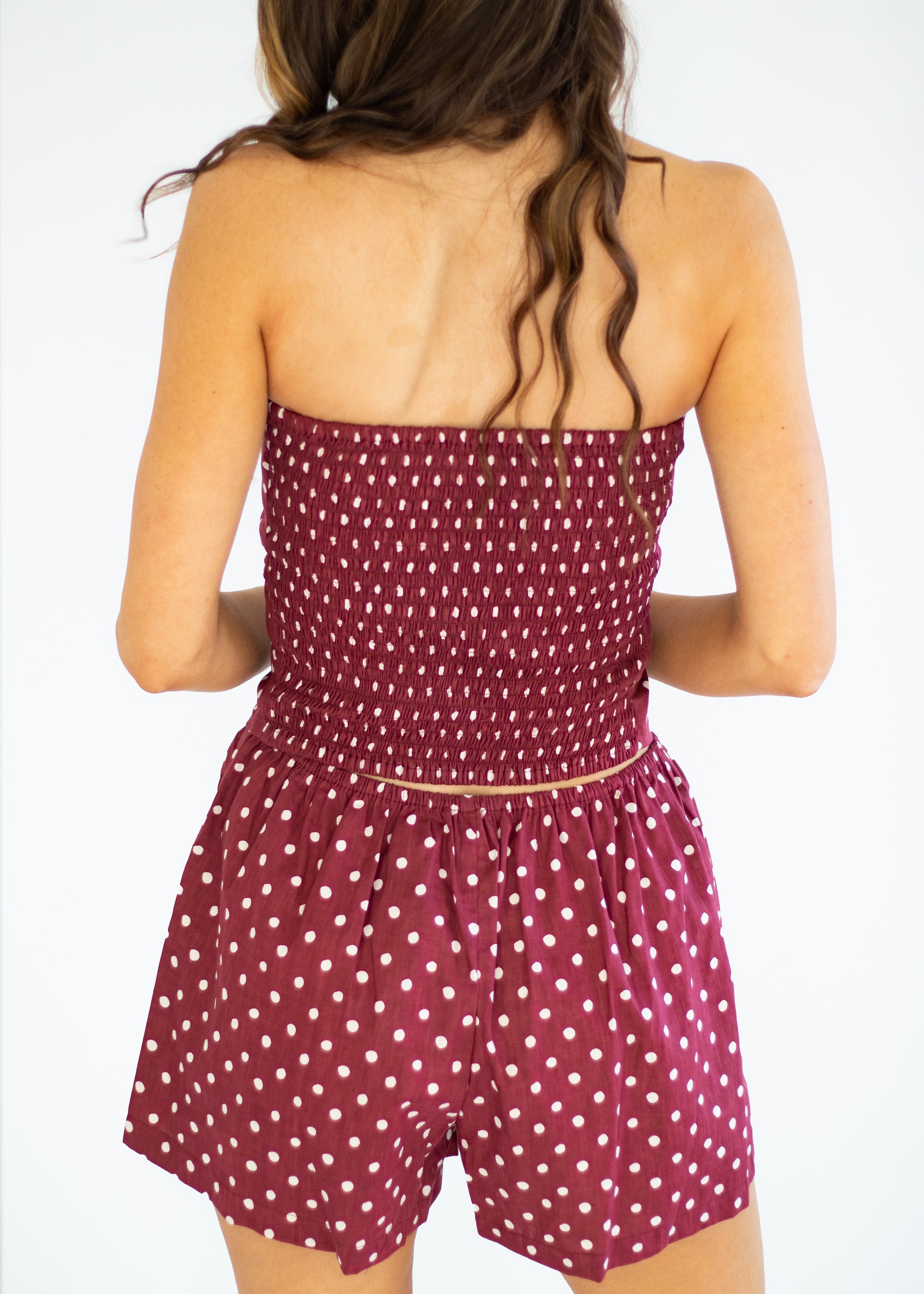 Woman wearing a polka dot romper on a plain background