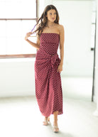 Woman wearing a red polka dot dress in a minimal indoor setting
