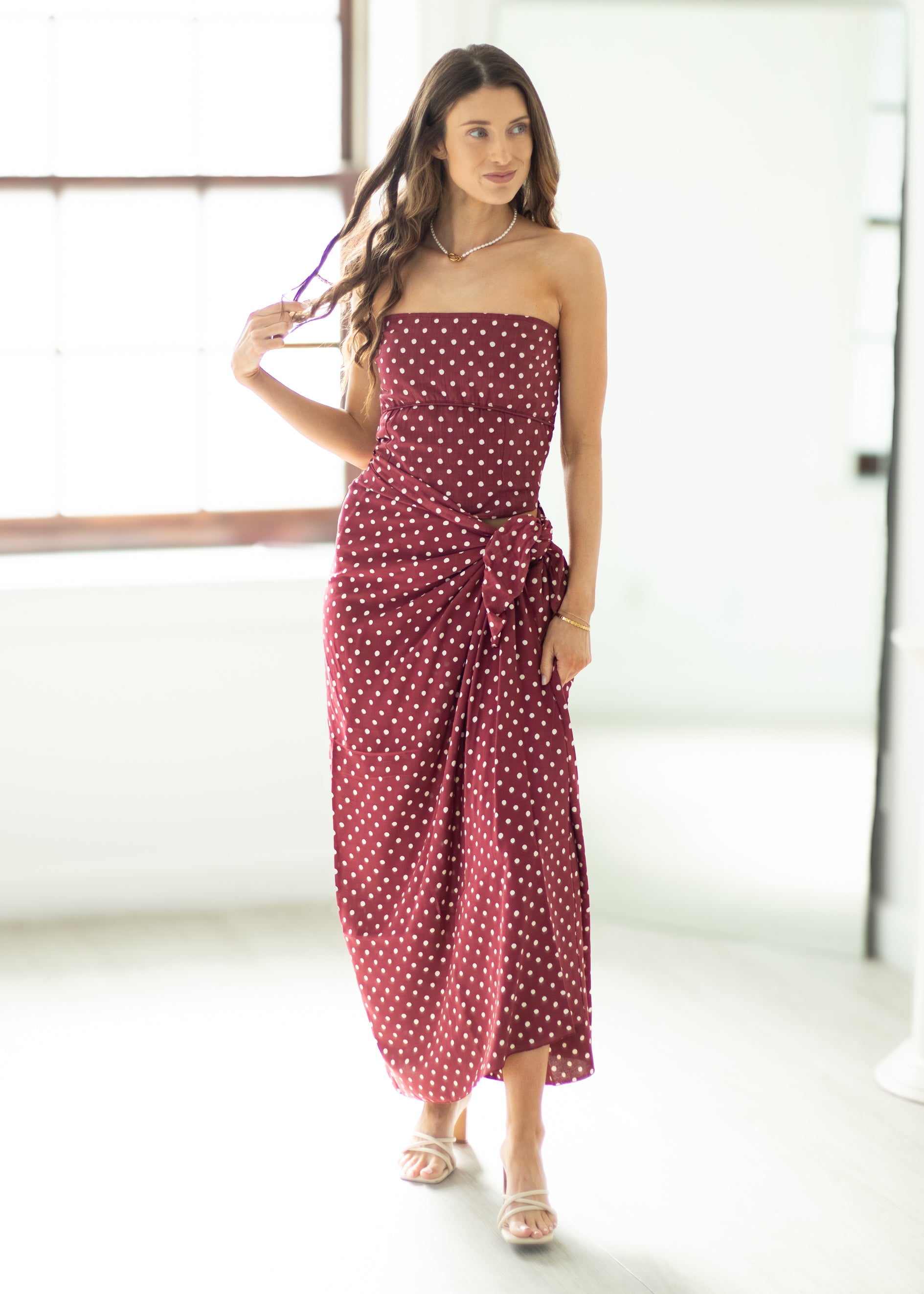 Woman wearing a red polka dot dress in a minimal indoor setting