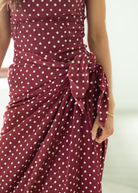 Maroon dress with white polka dots on a plain background