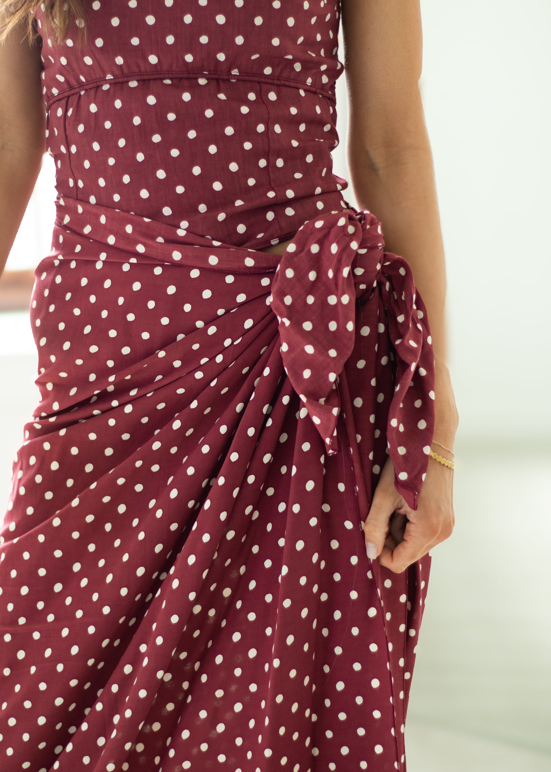 Maroon dress with white polka dots on a plain background