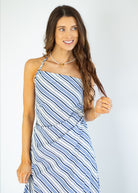 Woman wearing a blue and white striped dress against a plain background