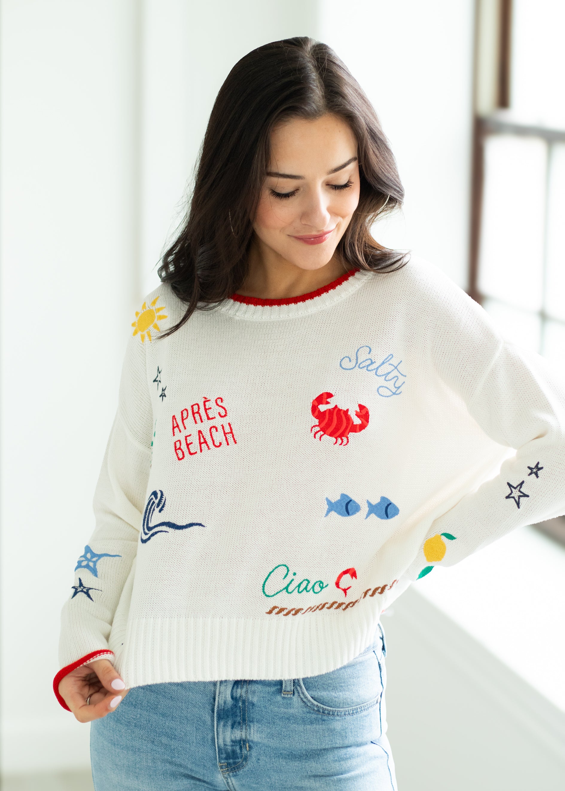 Woman wearing a white sweater with colorful graphics and text