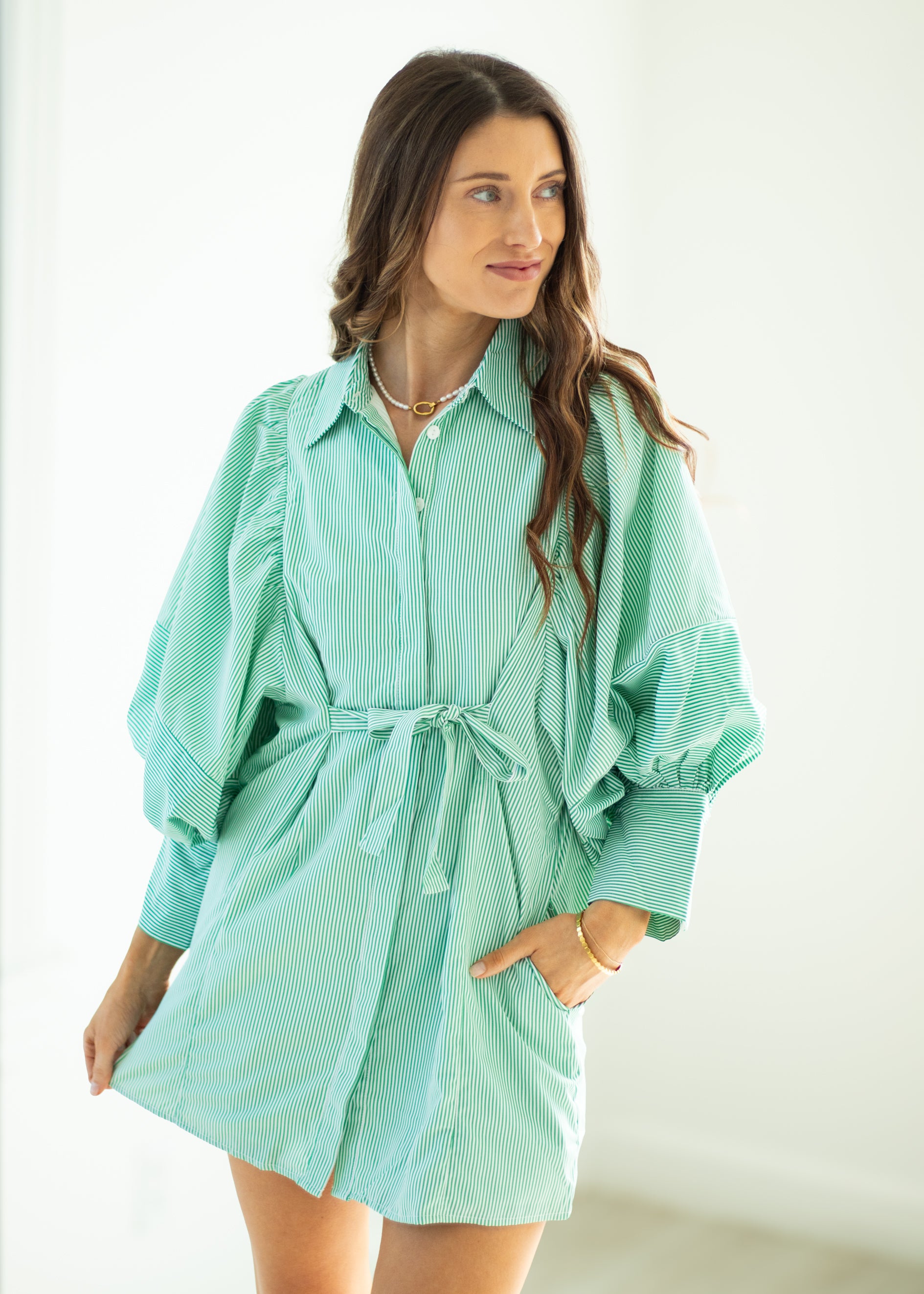 Woman wearing a light blue striped dress with a white background