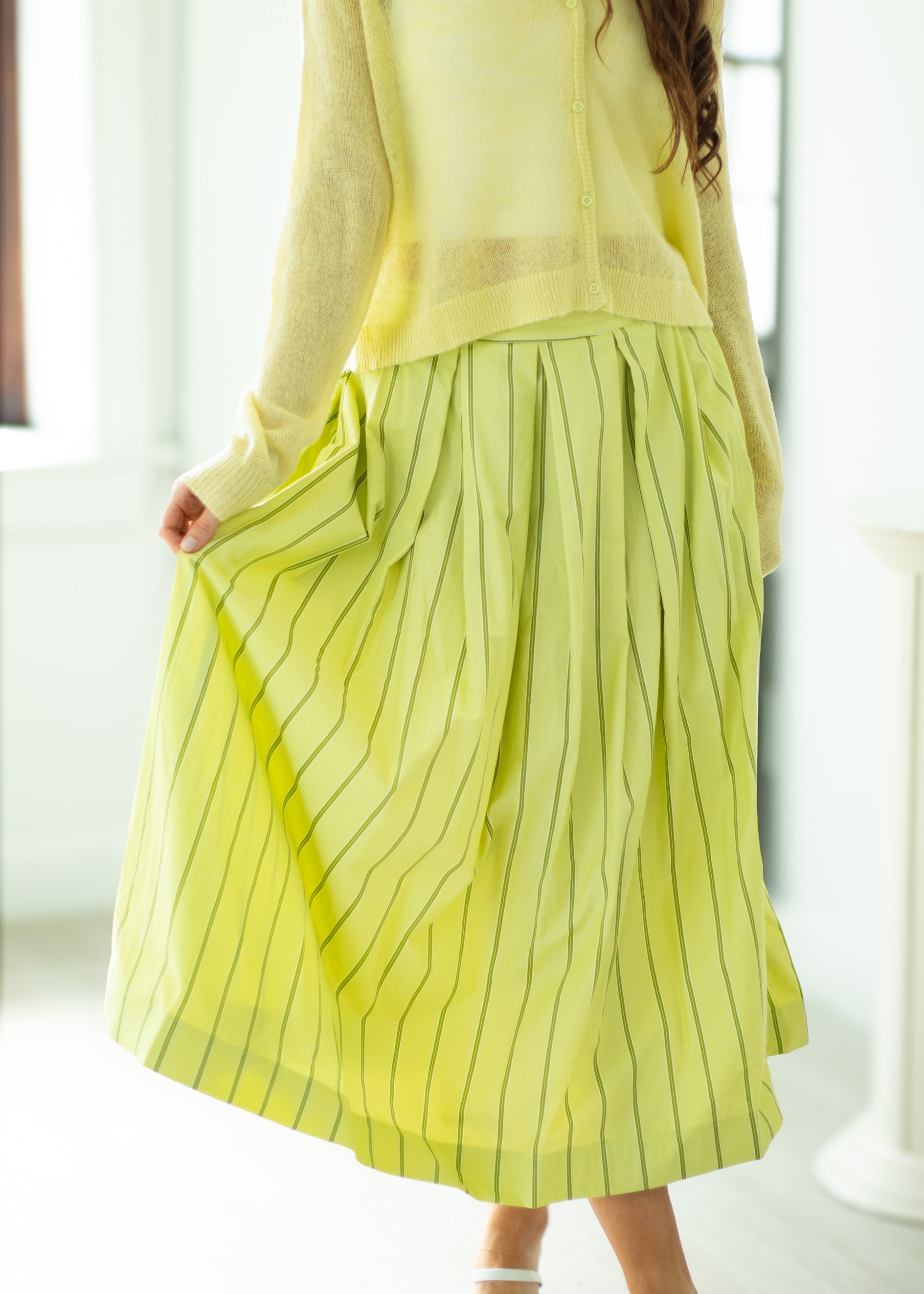 Person wearing a light green dress with pinstripes in a bright room.