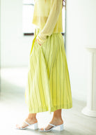 Person wearing a yellow outfit with wide-leg pants in a bright indoor setting