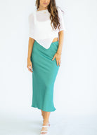 Woman wearing a white top and teal skirt on a white background