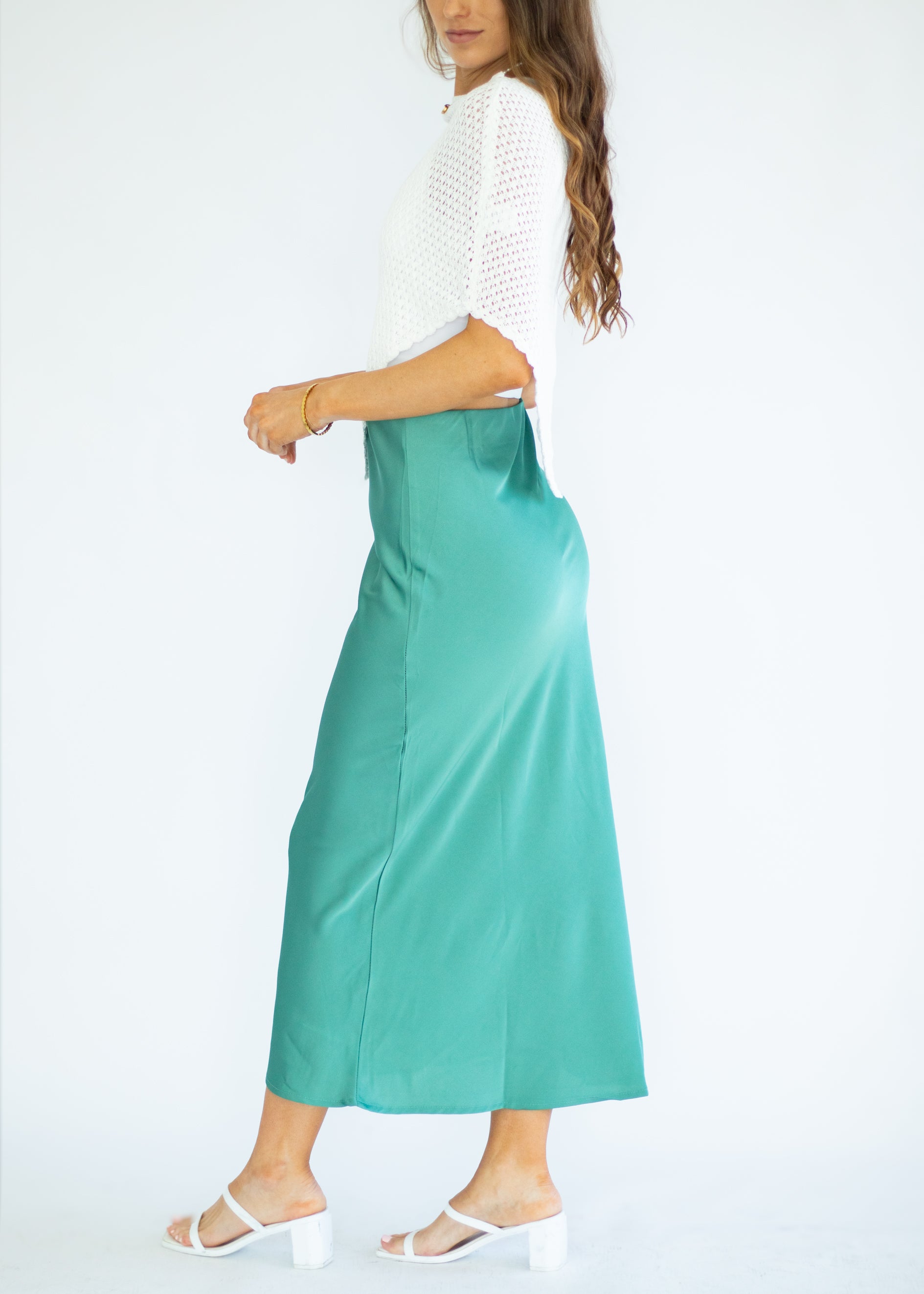 Woman wearing a white top and green skirt on a white background