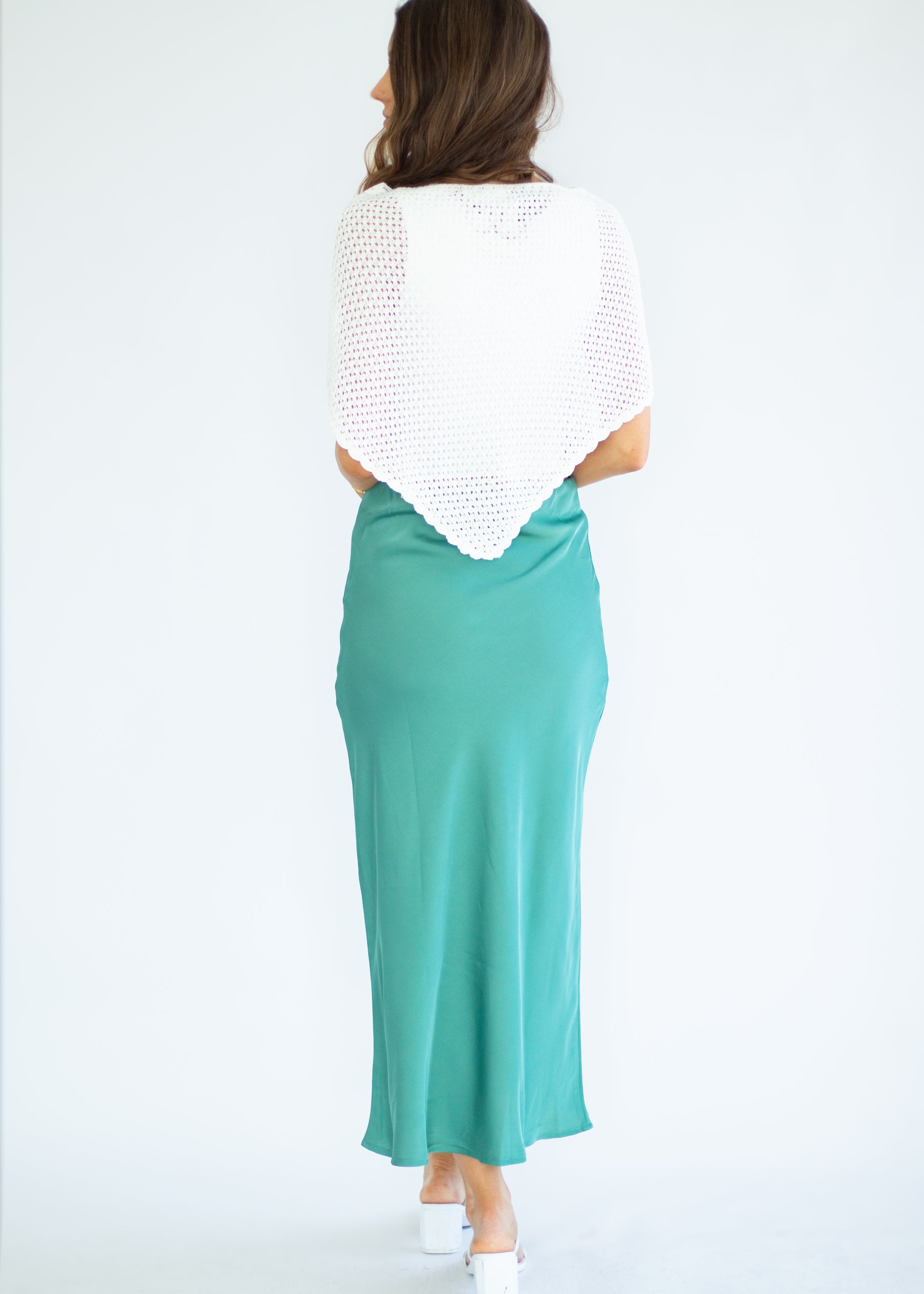 Woman wearing a white top and teal skirt on a white background