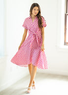 Woman wearing a pink patterned dress in a bright room