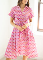 Woman wearing a pink patterned dress with a white background