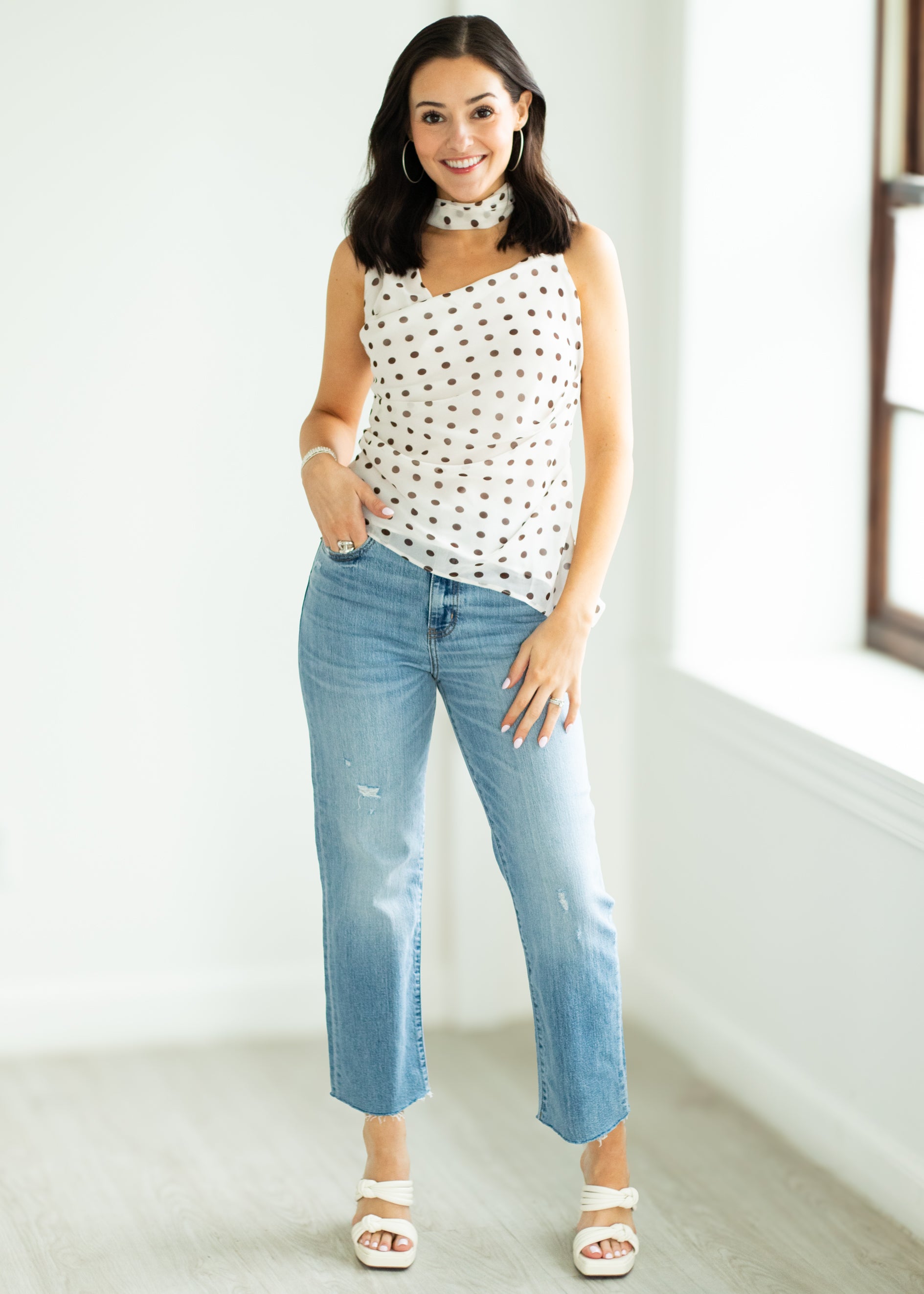 Woman wearing a polka dot top and blue jeans indoors.