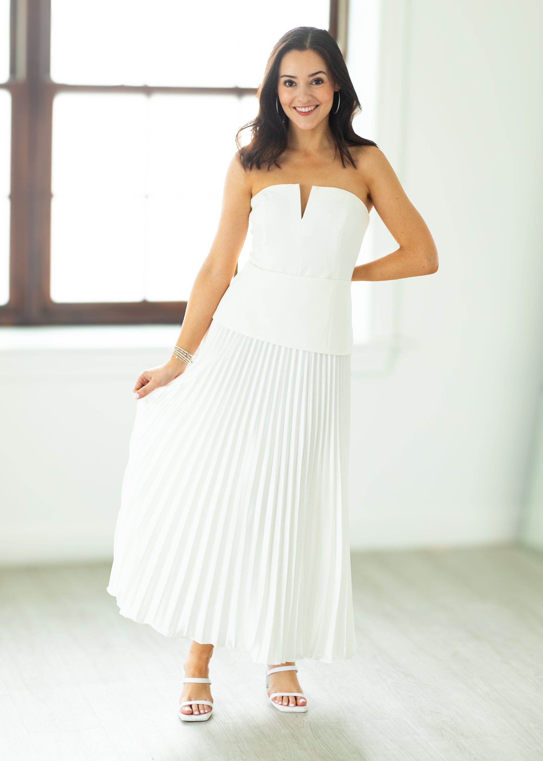Woman wearing a white strapless dress in a bright room