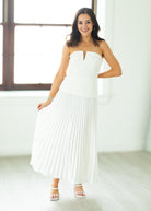 Woman wearing a white strapless dress in a bright room