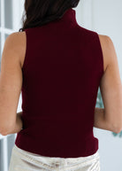 Person wearing a maroon sleeveless sweater with a blurred background