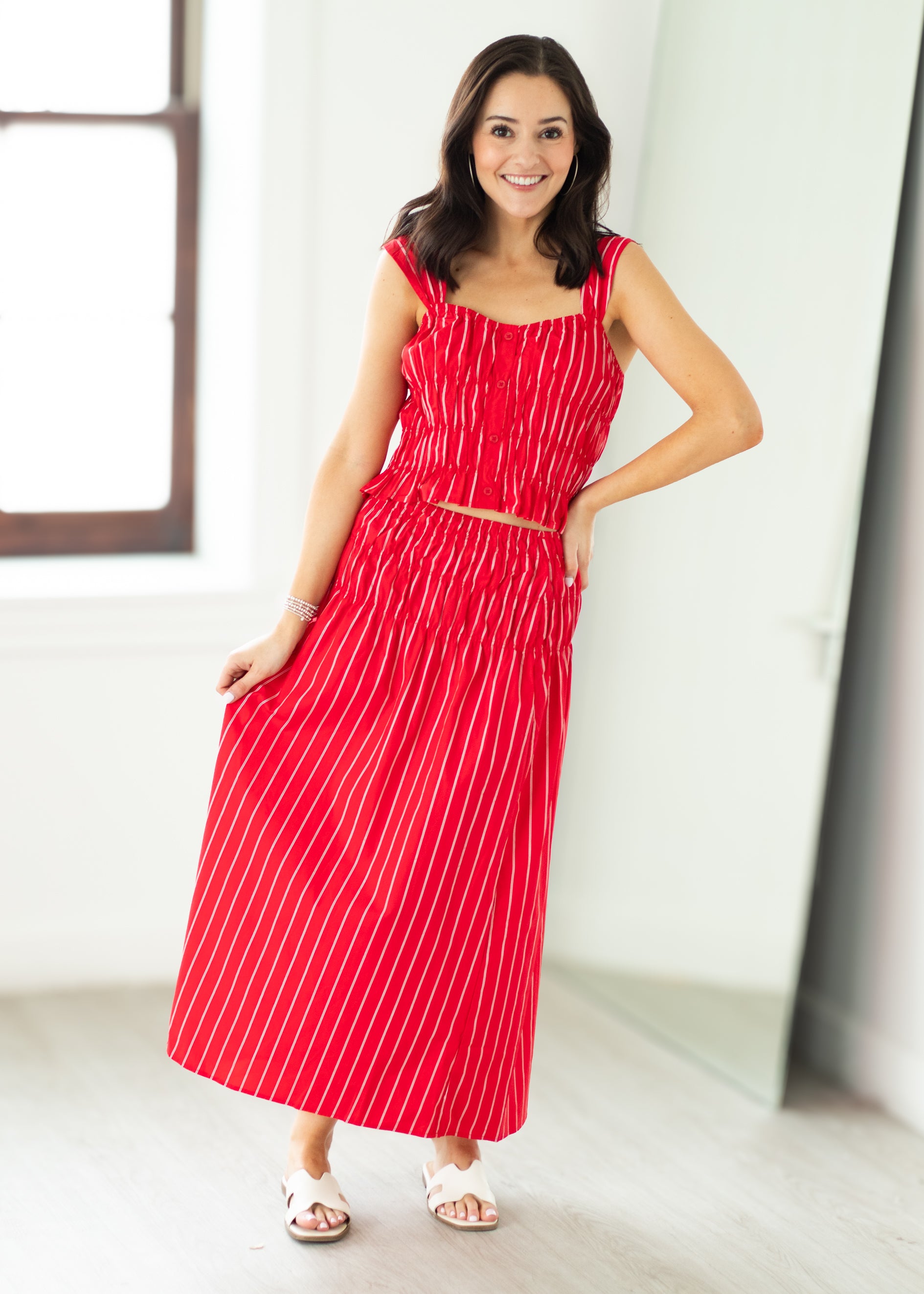 Woman wearing a red and white striped dress standing in a bright room.