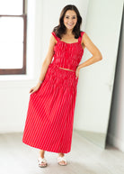 Woman wearing a red and white striped dress standing in a bright room.