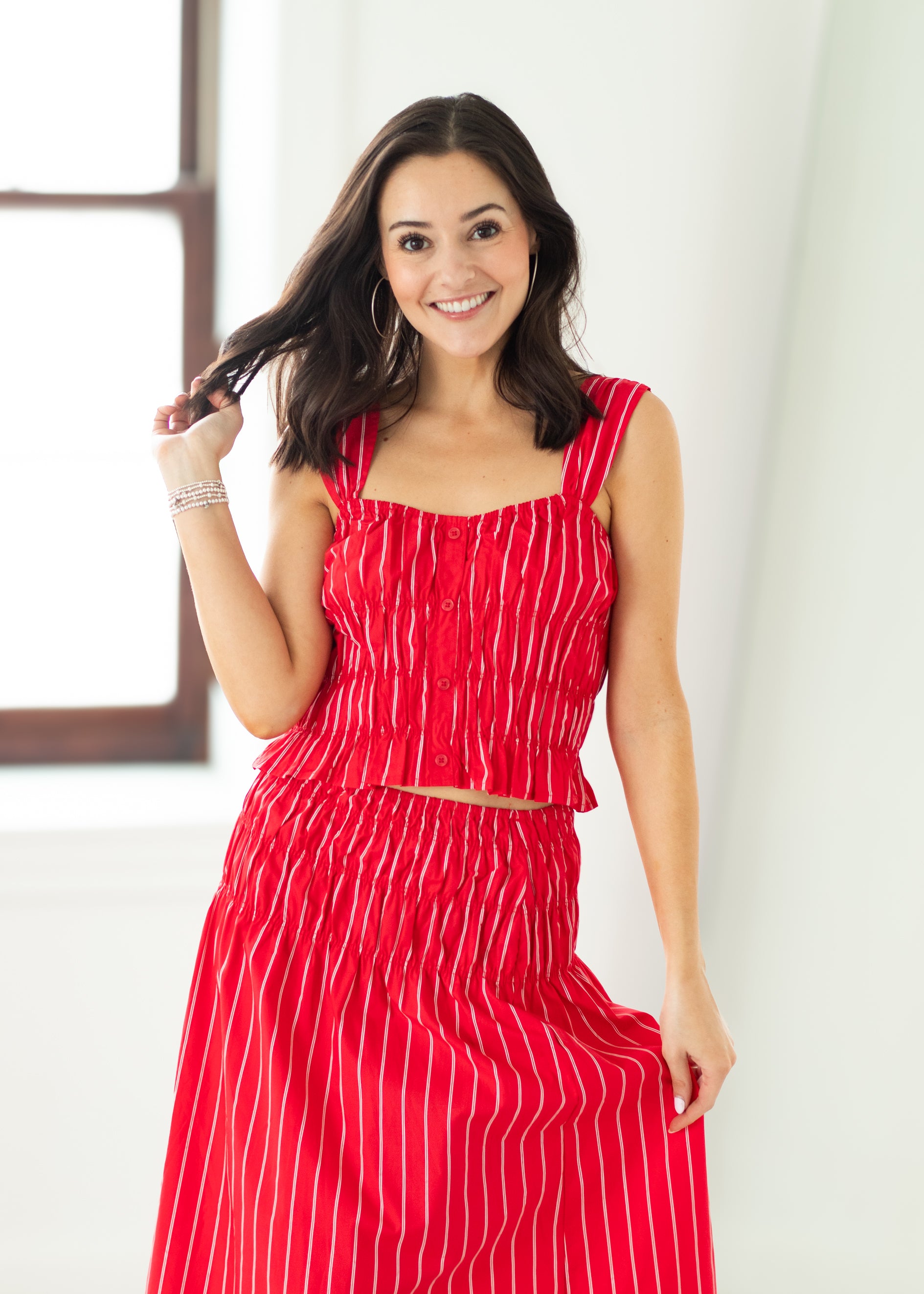 Woman wearing a red dress with white stripes against a white background