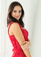 Woman wearing a red dress with white patterns against a white background