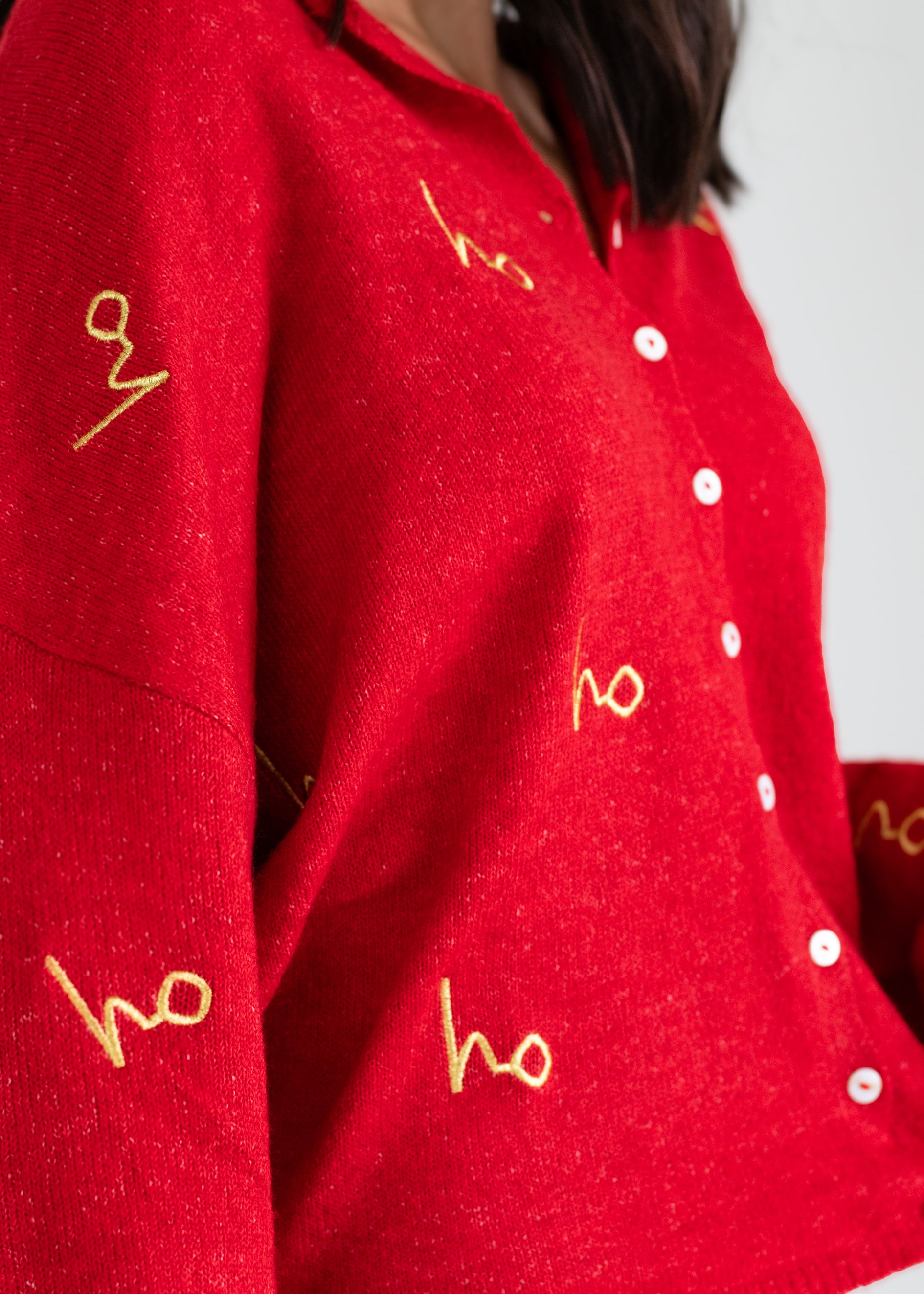 Red sweater with gold 'ho' text and white buttons on a plain background