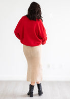 Person wearing a red sweater and gold skirt on a white background